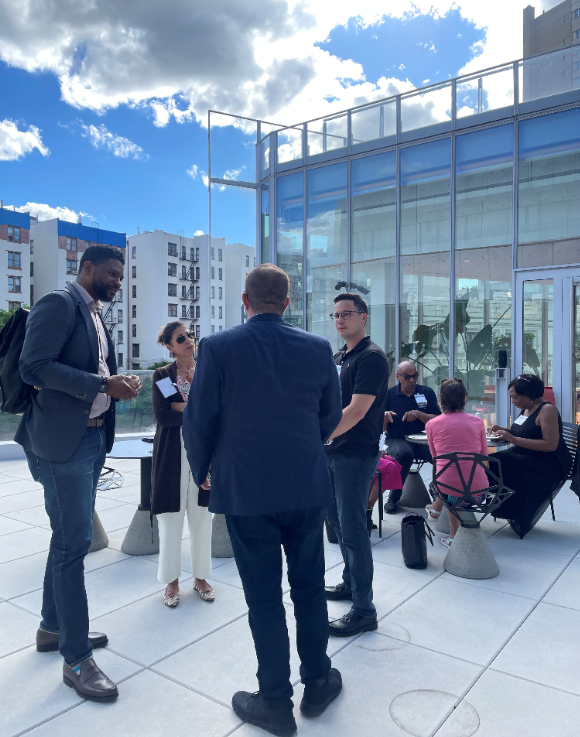 The CU Grow Vendor Development program hosted its first in-person procurement event since the beginning of the pandemic at The Forum at Columbia on June 9. Four people standing and speaking, and three people sitting at a table eating and speaking on a rooftop patio.